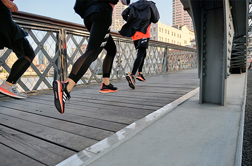 A group of people running across a bridge, modelling Adidas trainers.