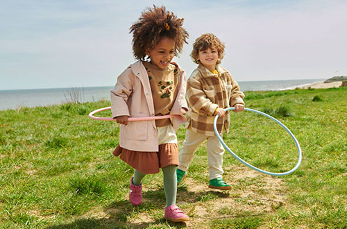 Two children playing in a field, wearing Start Rite shoes.
